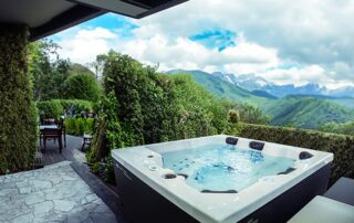 Whirlcare Whirlpool Magic Softub Schweiz in anthrazit auf einem Gartensitzplatz mit Blick aufs Land und in die Berge.