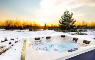 Whirlcare Whirlpool Magic Softub Schweiz in anthrazit gefüllt auf einer schneebedeckten Terrasse mit Blick aufs Land bei Morgendämmerung.